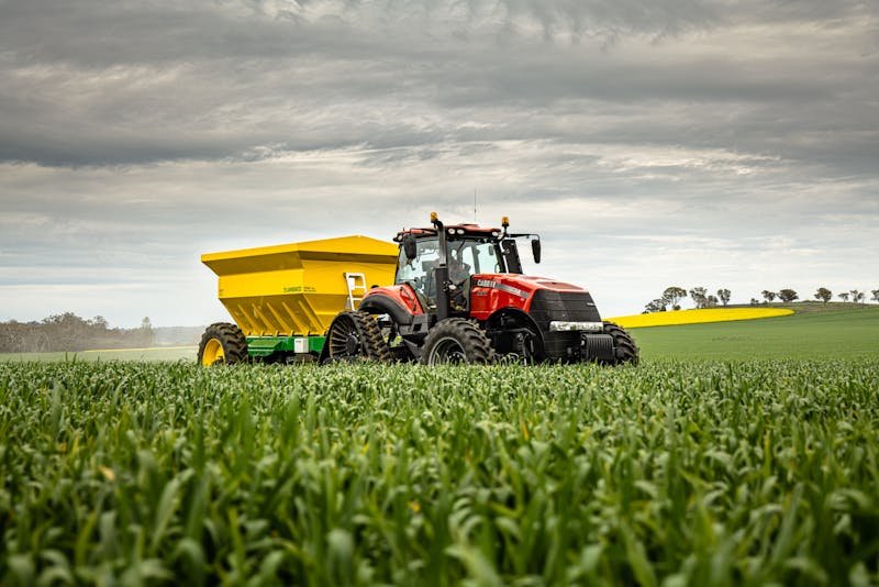 Agricultural tractor working in green crop field